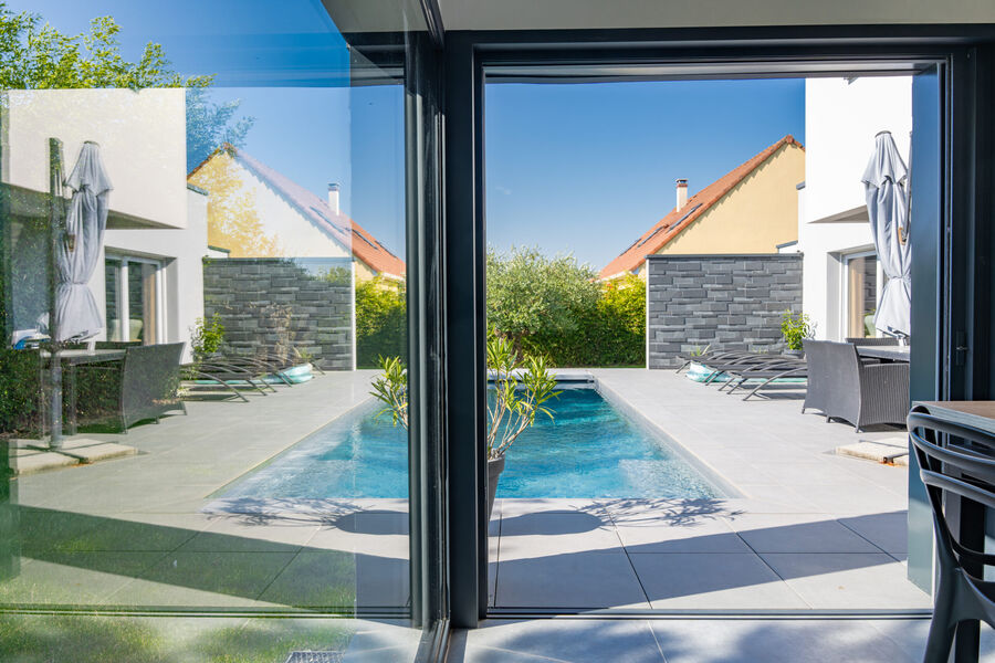 Porte-fenêtre ouverte sur la terrasse et la piscine