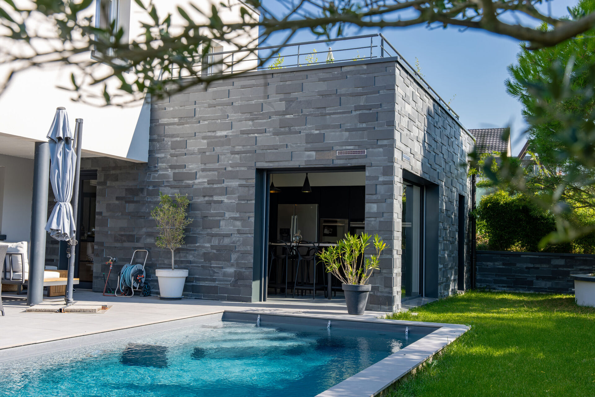 Entrée d'une maison contemporaine avec porte aluminium et bardage pierre
